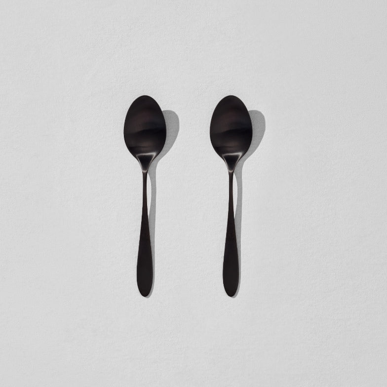 Overhead view of two satin black breakfast spoons