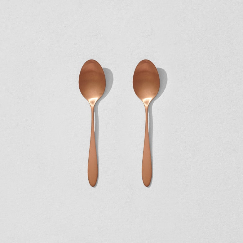 Overhead view of two satin copper breakfast spoons
