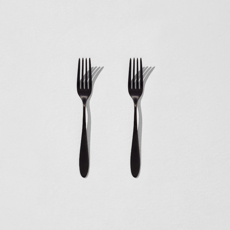 Overhead view of two satin black dessert forks