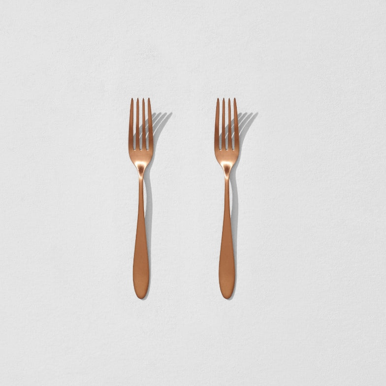 Overhead view of two satin copper dessert forks