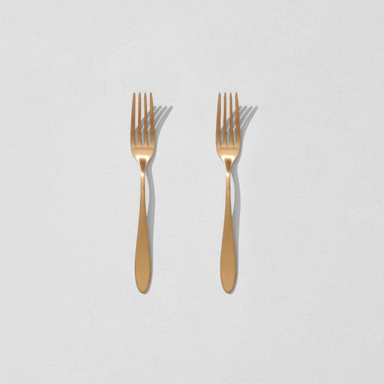 Overhead view of two satin gold dessert forks