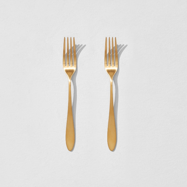 Overhead view of two satin gold dinner forks
