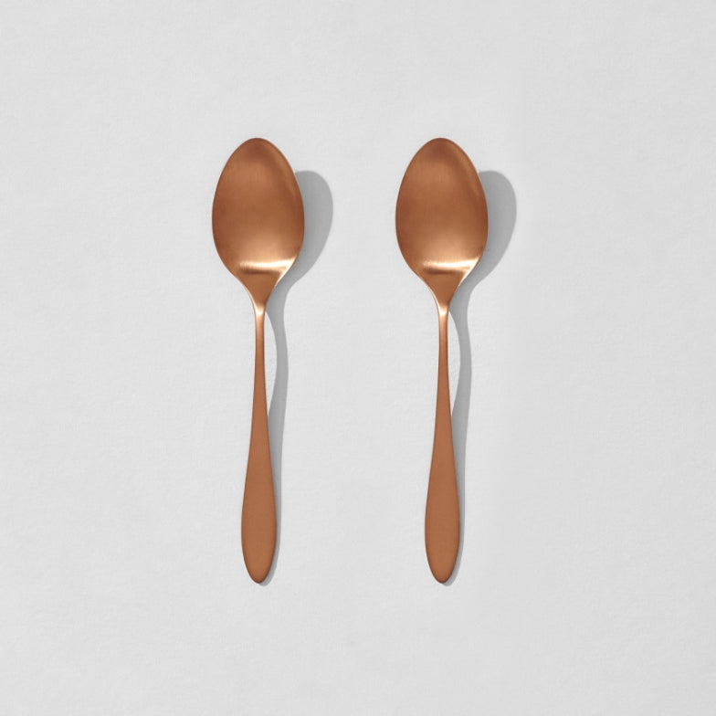 Overhead view of two satin copper dinner spoons