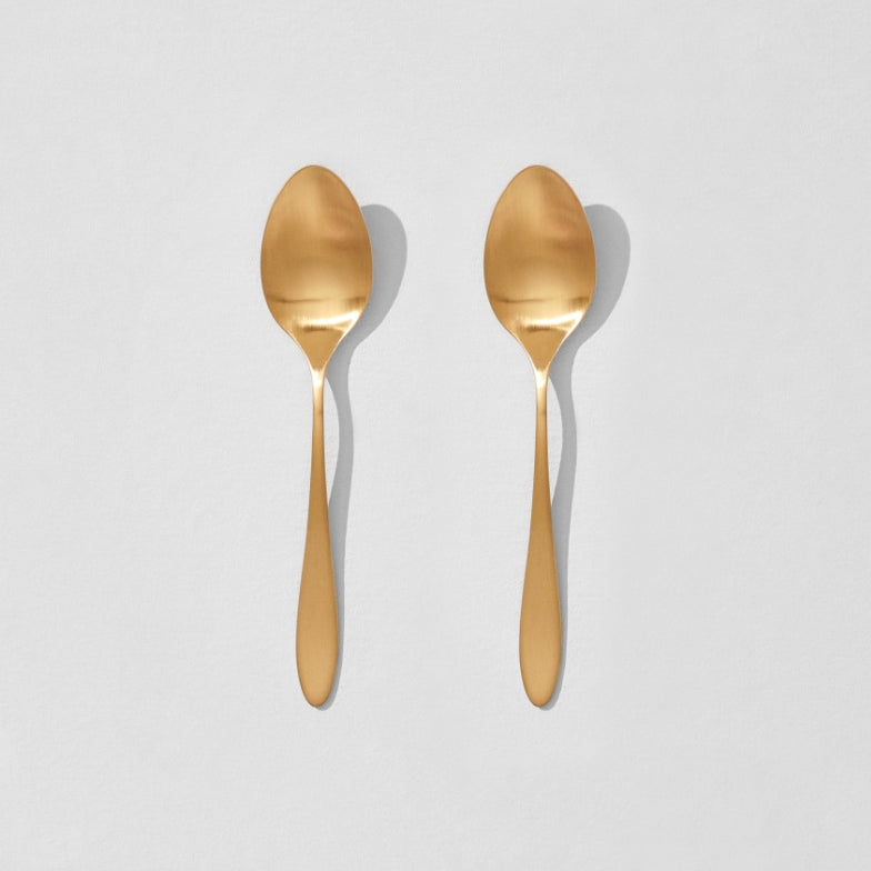 Overhead view of two satin gold dinner spoons