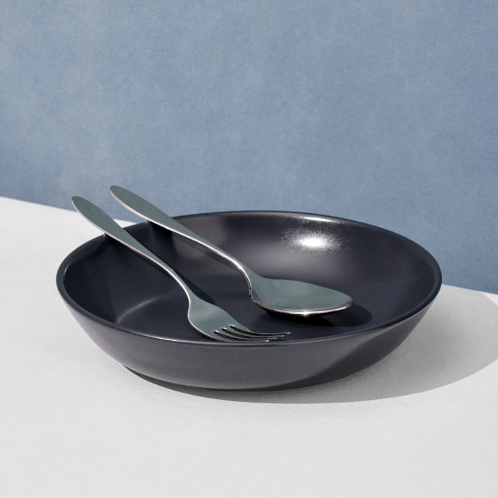 Classic stainless steel flatware set in charcoal navy serving bowl