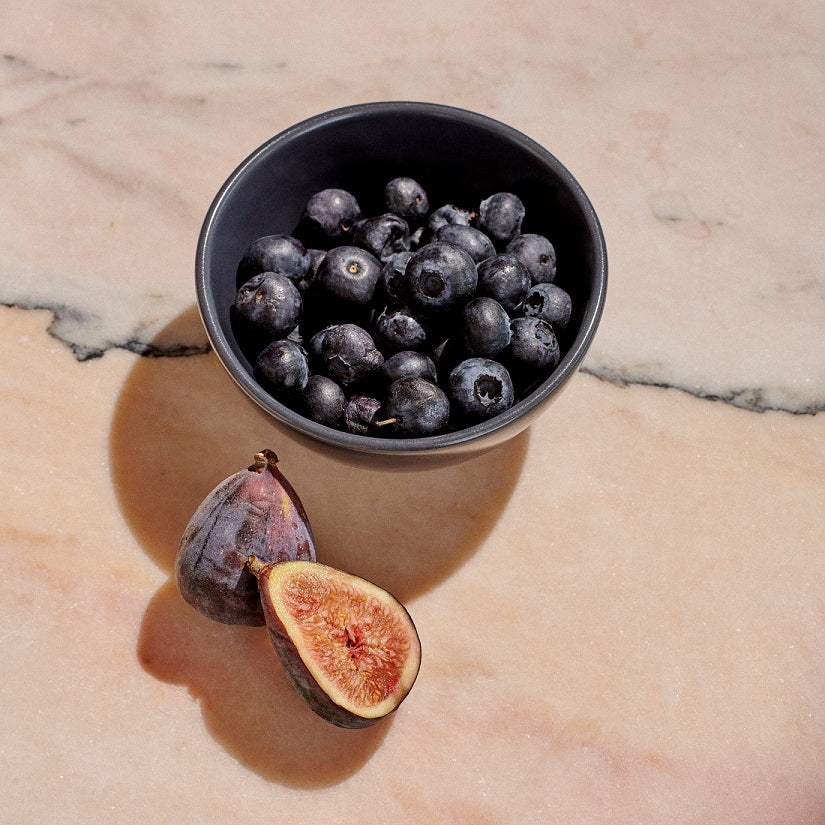 Charcoal navy mini bowl filled with blueberries next to two figs